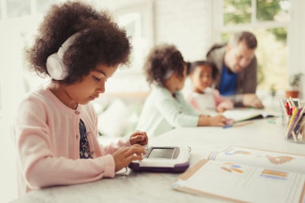 Girl with headphones using digital tablet doing homework at table