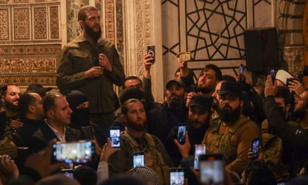 most are wearing khaki shirts and military fatigues, and many in the audience are filming him