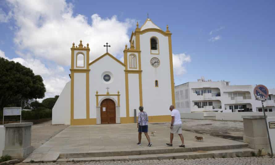 A couple walk in front of the church in Praia da Luz where the McCanns came to pray