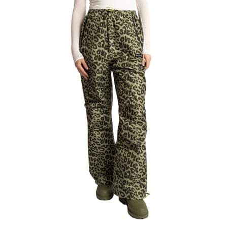 A person wears olive leopard-print rain trousers and matching boots with a white top