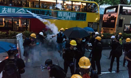 A protester throws back a tear gas round as thousands marched on police headquarters in their fight against the Hong Kong government