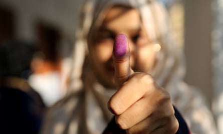 A woman displays her inked thumb after casting her vote.
