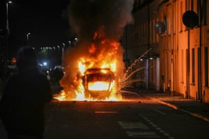 A vehicle burning at night in a residential street