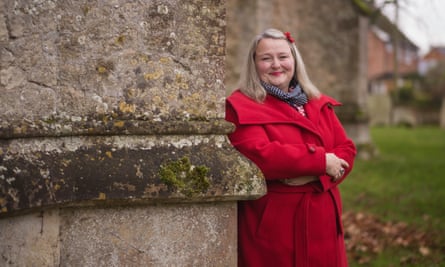 Prof Arlene Holmes-Henderson: she has long blond hair and wears a bright red coat as she stands by an old stone building.