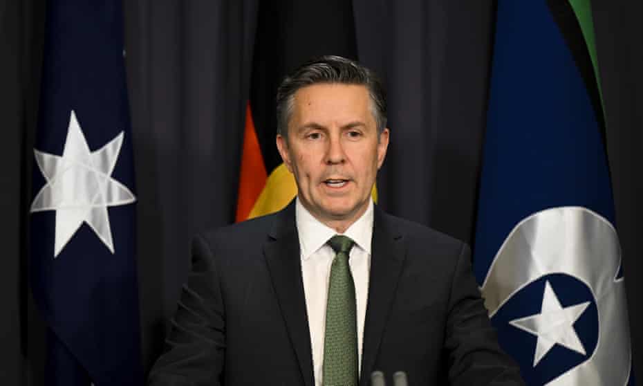Mark Butler standing in front of the Australian, Aboriginal and Torres Strait Islands flags