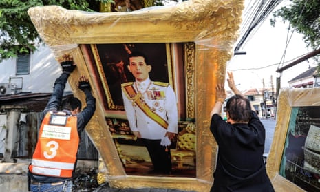 Workers lift a portrait of Maha Vajiralongkorn