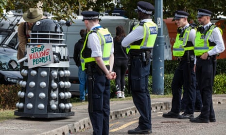 Met officers observe a Dalek bearing a sign saying ‘Stop Killing People’ at a protest against DSEI.