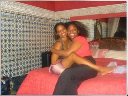 Two women sitting on a bed, smiling and higging each other