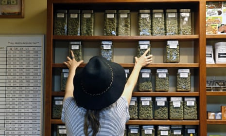 An employee arranges glass display containers of marijuana on shelves at a retail and medical cannabis dispensary in Boulder, Colorado on 11 August 2016.