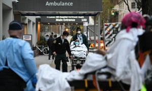 A man is wheeled out of Lenox Hill hospital in Manhattan as a woman, foreground, is wheeled into the emergency room on Friday, as the daily death toll from the coronavirus outbreak in the city neared 800 for the third straight day.