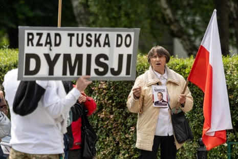Opponents of Poland's prime minister Donald Tusk hold a banner reading "Tusk's Government - Step Down" and a portrait of president-elect Karol Nawrocki in front of Parliament before the vote of confidence for his cabinet in Warsaw.