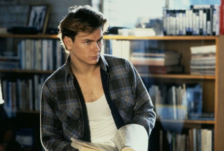 A boy in a plaid shirt and white vest in a room full of books