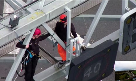 A specialist police officer attempts to remove a Just Stop Oil protester from the gantry over junction 30 of the M25 on Wednesday.