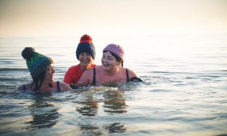 Friends swimming in the sea on a wintry-looking day.