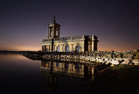 A church reflected in still water under a night sky