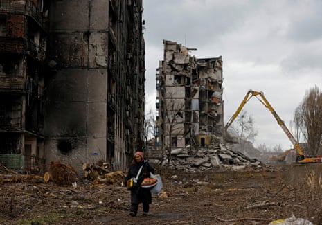 Una mujer pasa junto a bloques de apartamentos destrozados en Mariupol ocupado.