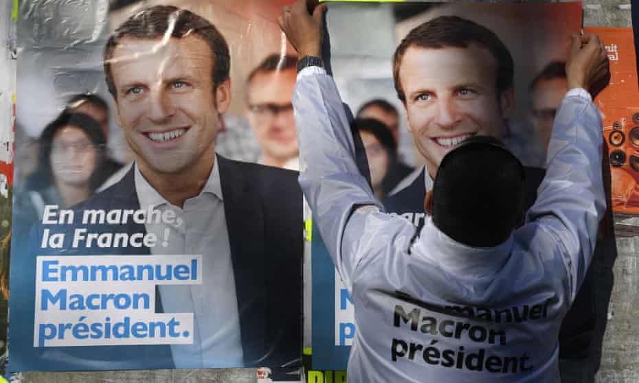 A supporter of French presidential election candidate for the En Marche ! movement, Emmanuel Macron, puts up electoral posters i