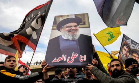 Os manifestantes acenam bandeiras e seguram um pôster de Hassan Nasrallah, o falecido líder do Hezbollah, em uma manifestação em Beirute