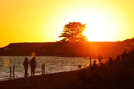 Visitors walking along Campbells Cove Beach in Melbourne during sunset