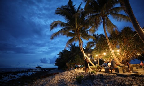 People gather at an outdoor cafe next to the Pacific Ocean at dusk in Funafuti, Tuvalu, which like many Pacific nations has had no confirmed cases of coronavirus.