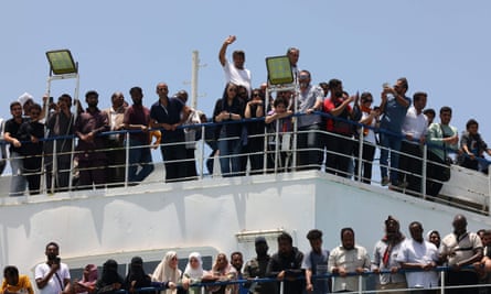 Crowds of people at the railing of a boat waving to the camera