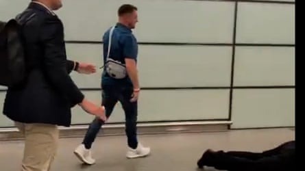 A screengrab of a video showing Tommy Robinson and another person walking past someone lying on the ground