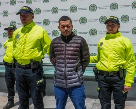 Elder Jose Arteaga Hernandez flanked by cops in hi viz jackets.