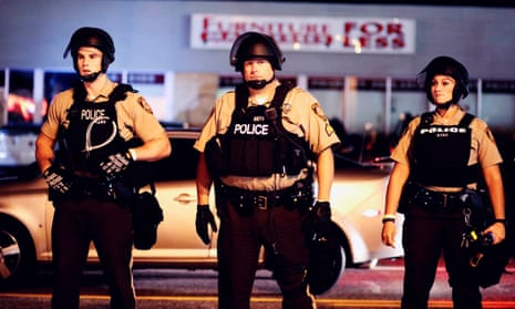 Police stand guard during a protest in Ferguson on the anniversary of the shooting of unarmed 18-year-old Michael Brown