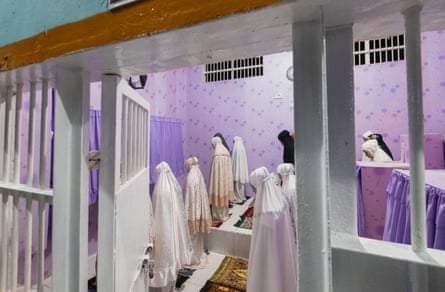 A group of women wearing white veils prey in a dedicated space in a prison