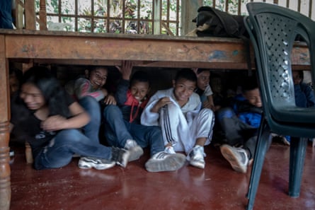 The children find shelter under a table during a simulated evacuation after a possible bomb explosion or gunshot attack