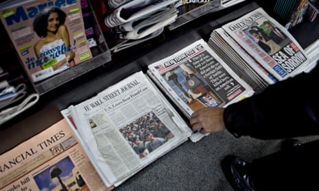 A customer picks up a copy of a newspaper at a newsstand in New York, US.
