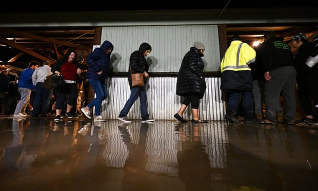 People cross a puddle of water at the Birdsville pub ahead of the 140th anniversary of the Birdsville races.