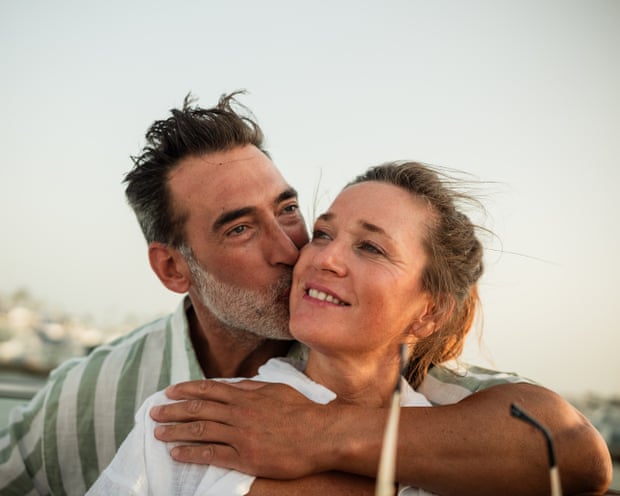 Mature couple kissing on a boat at sunset