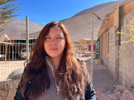 A young Indigenous woman, with a desert landscape in the background.