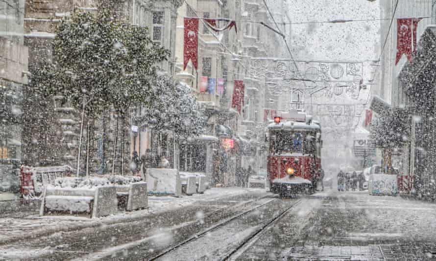 People walk along Taksim Square as snow falls in Istanbul