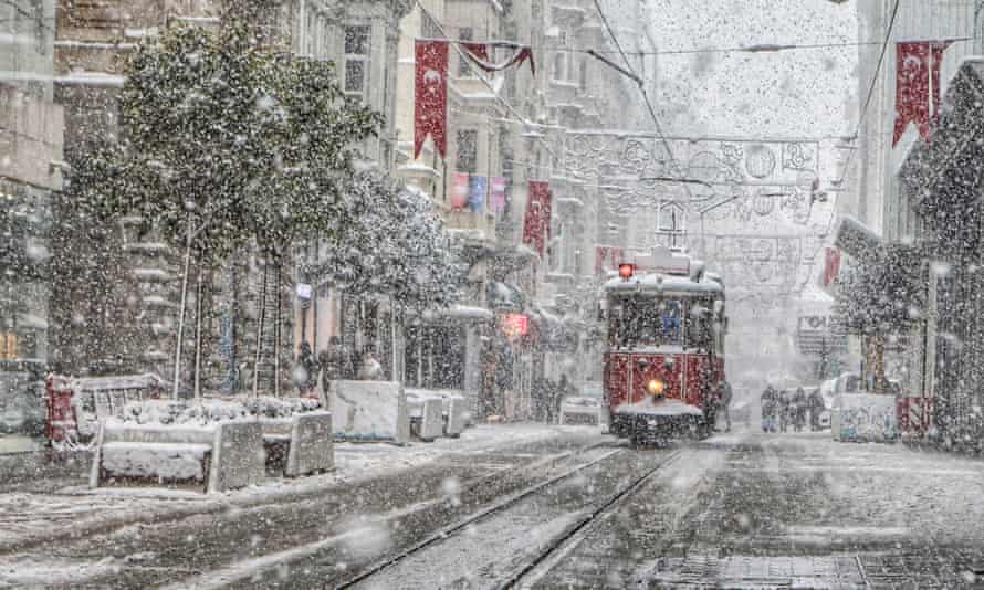 People walk through Taksim Square as snow falls in Istanbul