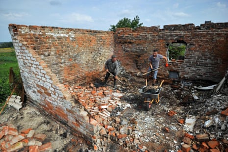Men clean a destroyed house in the village of Kukhari, Kyiv region