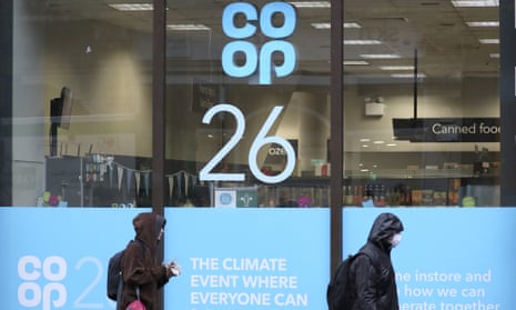 Pedestrians walk past a shop window advertising the COP26 climate conference in Glasgow, Scotland