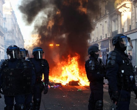 Riot police stand near a large fire during civil unrest in Paris