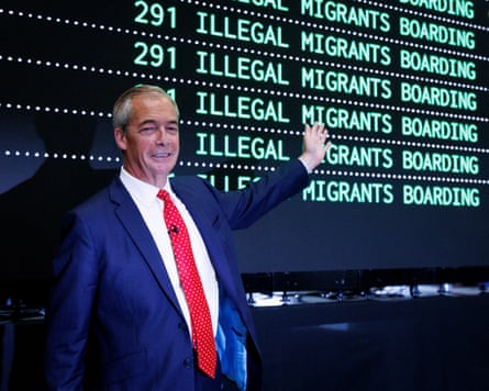 Nigel Farage poses for a political stunt, his arm waving in front of a fake departure board that reads ILLEGAL IMMIGRANTS BOARDING