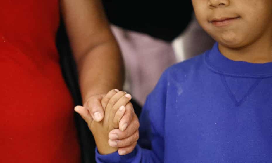 A mother and son who were separated at the US border hold hands following their reunion.