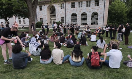 Three dozen students sit in a neat rectangle on a green lawn.