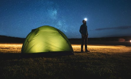 Man standing by a tent looking at stars