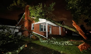A tree is downed next to a suburban home.
