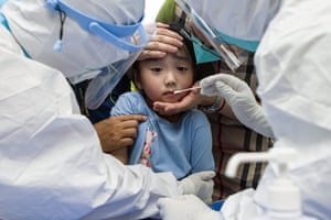 A child reacts to a throat swab during mass testing for Covid-19 in Wuhan