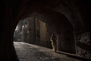 A woman walks down an alley in the Old City of Jerusalem at the start of the fasting month of Ramadan