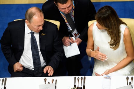 Vladimir Putin and Melania Trump sit next to each other at a table and talk