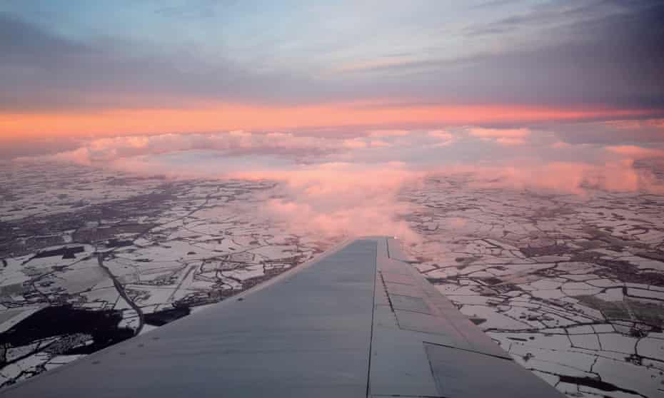 View of snow-covered fields and wing in foreground from British Airways plane