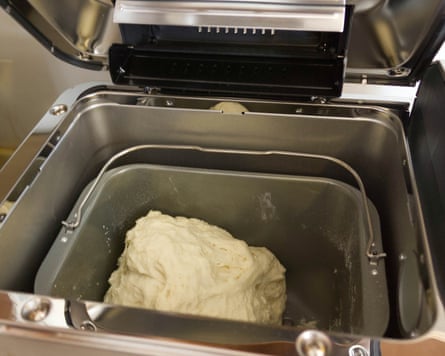A mound of pale dough sits inside an open metal bread maker’s baking pan