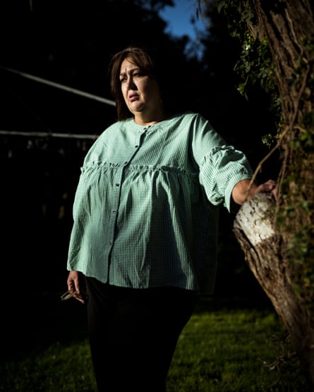 Jeannie Marie-Blake stands in her garden and leans against a tree with her hand
